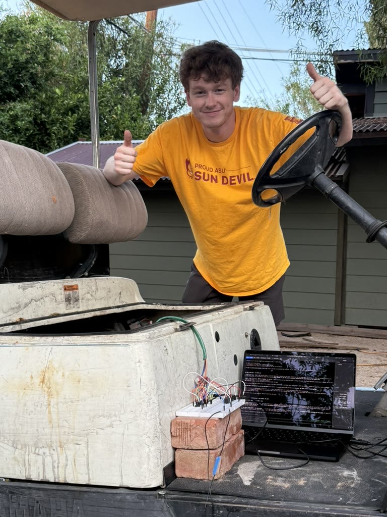 Jacob giving a thumbs up behind the cart, with the breadboard and laptop on the floorboard